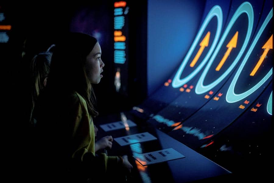 A young child playing the interactive "Eat or Be Eaten" game inside Monterey Bay Aquarium